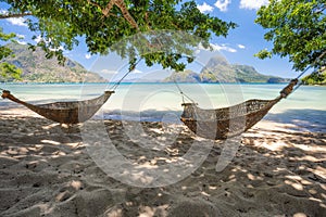 El Nido, Palawan, Philippines. Bamboo hammocks on shore in the shade. Beautiful tropical lagoon with epic Cadlao island