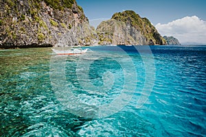 El Nido, Palawan, Philippines. Banca boat in crystal clear ocean water near Matinloc island, highlights of hopping trip