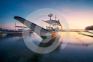 El Nido, Palawan, Philippines. Traditional banca boat in the beach bay in golden sunset light. Tranquil scenic bacuit