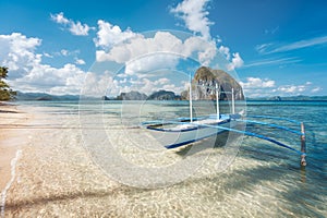 El Nido, Palawan, Philippines. traditional banca boat on sandy beach with crystal clear water on morning island hopping