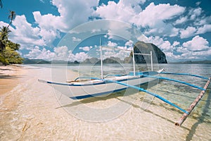 El Nido, Palawan, Philippines. White banca boat on sandy beach with crystal clear water ready for island hopping trip