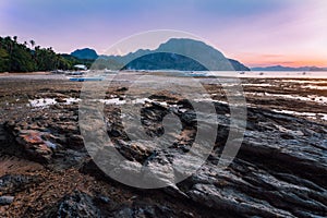 El Nido village with local banca boats on shore lit by sunset light at low tide. Picturesque nature scenery. Palawan