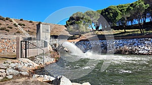 El Pardo Reservoir, in the Community of Madrid, expelling water into the Manzanares River. Pine trees in the background, in Spain. photo