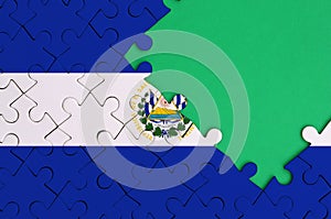 El Salvador flag is depicted on a completed jigsaw puzzle with free green copy space on the right side