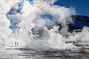 El Tatio geysers in Chile, Silhouettes of tourists among the steams at sunrise photo