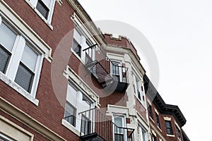 Elaborate architectural details on windows, overhangs, and top edge of a classic urban apartment building, metal balconies