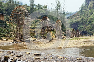 Elaborate water wheels made from bamboo with trees in the background in summer at Cat Cat Village in Sa Pa, Vietnam