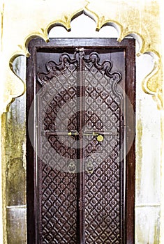 Elaborately carved wooden door with intricate patterns, set within a decorative scalloped archway. photo