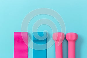 Elastic expanders and pink dumbbells on blue background copy space