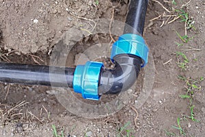 Elbow fitting and pvc pipes at bend in dirt trench outdoors