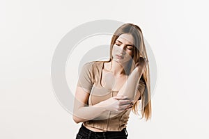 Elbow injury of girl on white background. Traumatology. Attractive girl with pain and bruise in her arm due to an