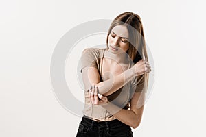 Elbow injury of girl on white background. Traumatology. Attractive girl with pain and bruise in her arm due to an