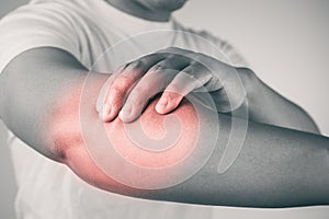 Elbow injury from tennis and golf. The man uses fingers to massage his arm. Pain symptom area is shown with red color. Healthcare