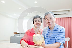 Eldely couple hold piggy bank