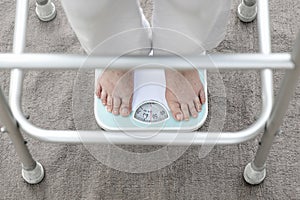 Eldely female standing on weight scale , her weight measure 54