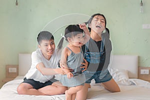 Elder asian sister and Elder brother play and dance with younger asian sister on a bed, Happy childhood