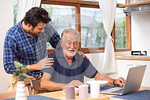 Elder care in home, good mentor healthy smart old man using laptop computer stay at young man