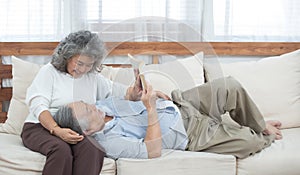 Elder couple sit on couch read book at home