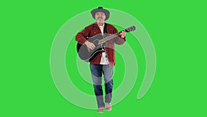 Elder cowboy walking, singing and playing guitar on a Green Screen, Chroma Key.