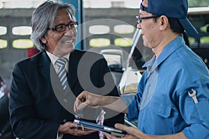 Elder customer show happy face in satisfy of mechanic`s service at garage and car maintenace service station photo