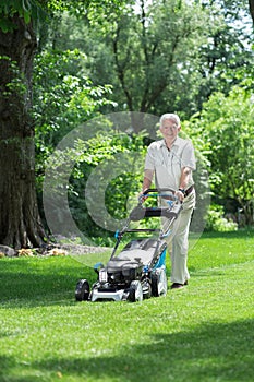 Elder gardener mowing lawn