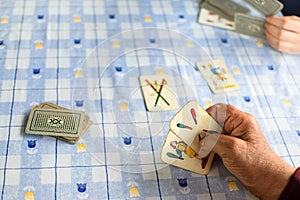 Elder hands playing cards on a blue table