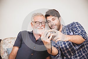 Elder looking replay photos from digital camera with his son happiness family moment with digital device concept