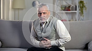 Elder male suffering stomach ache, sharp cramps in upper abdomen, indigestion photo