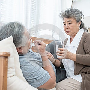 Elder man take pills while elder woman take care