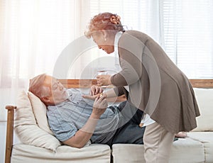 Elder man take pills while elder woman take care