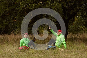 Elder people, woman and man in sports uniform hiking in autumn forest at sunny day, outdoors. Scandinavian walking