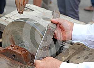 Elder while sharpening the blade of the knife on the water wheel