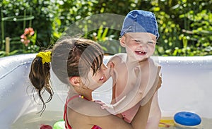 The elder sister and younger brother are indulging in an inflatable pool in the garden,