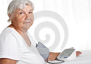 Elder woman measuring blood pressure with automatic manometer