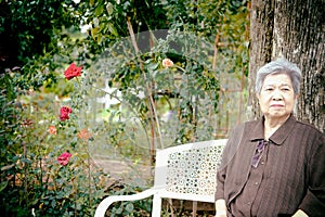 Elder woman resting in flower garden. elderly female relaxing outdoors. senior leisure lifestyle