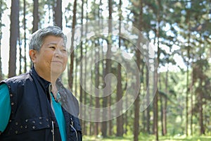 elder woman resting in pine tree forest. elderly female relaxing