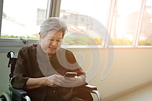 elder woman in wheelchair holding mobile phone. elderly senior using smartphone