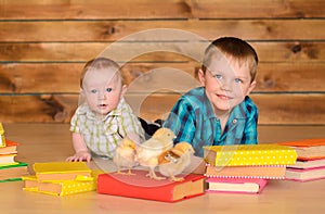 Elder and younger boys with books and chicks