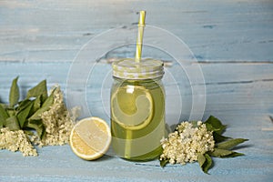 Elderberry flower flavored summer refreshment cocktail with sliced lemon isolated on wooden table