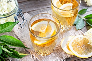 Elderberry flowers and lemon drink. Refreshing healthy summer juice. Glass of elderflower lemonade on wooden board. Alternative