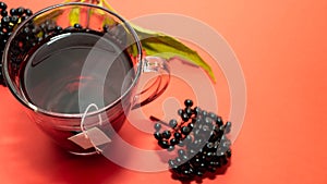 Elderberry tea on a red background top view. Ripe elderberry. Berry herbal tincture