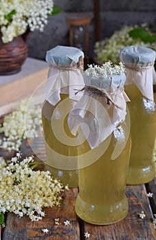 Elderflower cordial syrup and blossom flower in wooden background. Edible elderberry flowers add flavour and aroma to drink and de