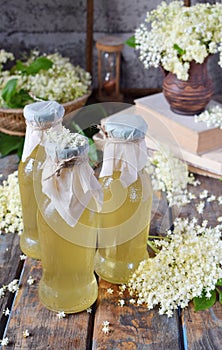 Elderflower cordial syrup and blossom flower in wooden background. Edible elderberry flowers add flavour and aroma to drink and