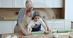 Elderly 60s grandma teach little 6s grandchild flattening dough