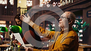 Elderly actor in a library focusing on script reading and memorization