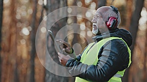 Elderly african american forestry engineer in noiseisolating headphones in forest old mature foreman forester thinks