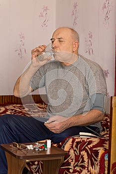 Elderly amputee sitting taking his medication