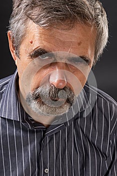 Elderly angry gray-haired man looking sullenly photo