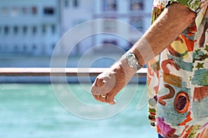 Elderly arm with expensive watch and flamboyant shirt on seafront