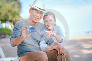 Elderly Asian couple holding a credit card with a smile Health insurance for the elderly, retirees